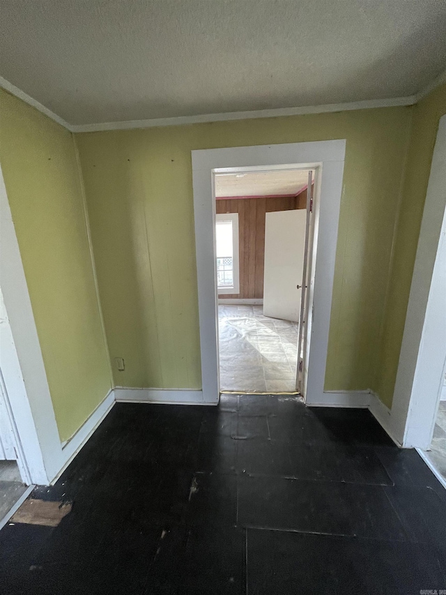 interior space with a textured ceiling, crown molding, and baseboards