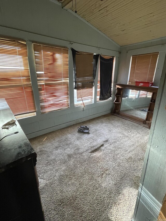 carpeted empty room featuring lofted ceiling and a sunroom