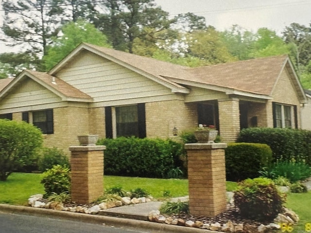 view of front of home with a shingled roof and brick siding