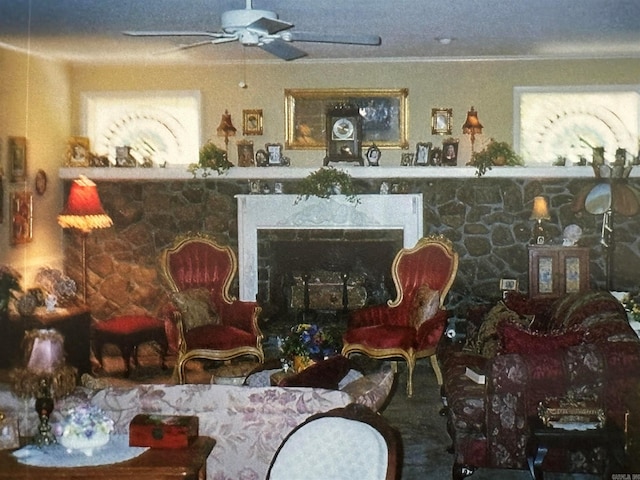 living area with ceiling fan, ornamental molding, and a fireplace