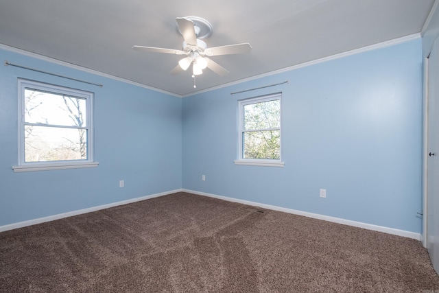 empty room with ornamental molding, carpet floors, baseboards, and a ceiling fan