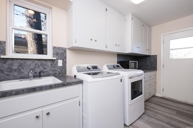 laundry area featuring a sink, wood finished floors, washing machine and dryer, and cabinet space