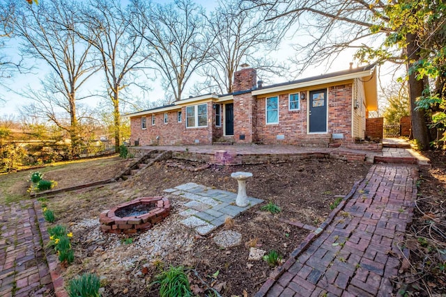 ranch-style house featuring brick siding, a patio, a chimney, an outdoor fire pit, and crawl space