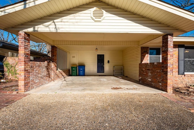 exterior space with driveway, a carport, and brick siding