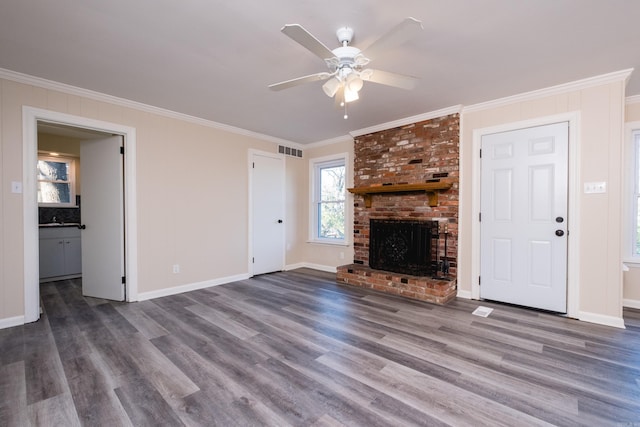 unfurnished living room with crown molding, a fireplace, visible vents, a ceiling fan, and wood finished floors