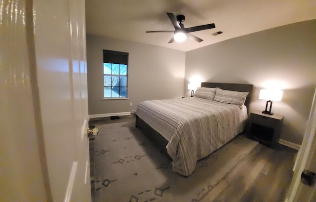 bedroom with a ceiling fan, wood finished floors, visible vents, and baseboards