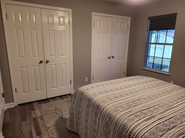 bedroom with dark wood-style floors, baseboards, and multiple closets