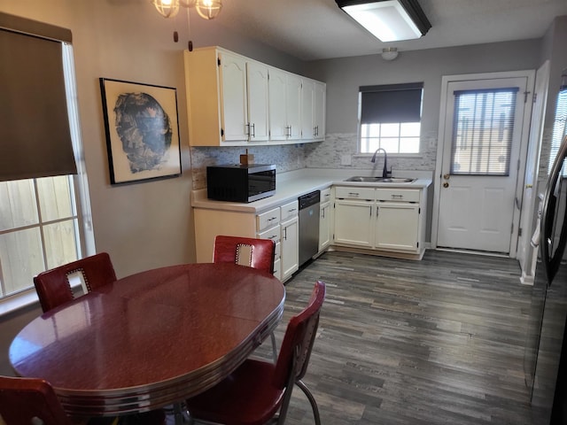 kitchen with dark wood finished floors, stainless steel appliances, light countertops, white cabinets, and a sink