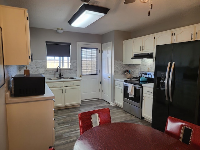 kitchen with black appliances, under cabinet range hood, dark wood-style floors, and a sink