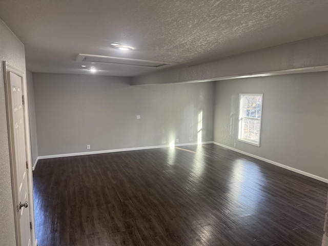 empty room featuring dark wood-style floors, a textured ceiling, and baseboards