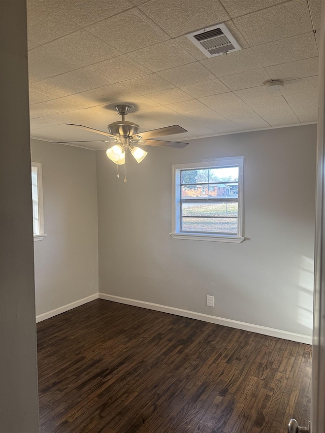 empty room with dark wood-type flooring, visible vents, ceiling fan, and baseboards