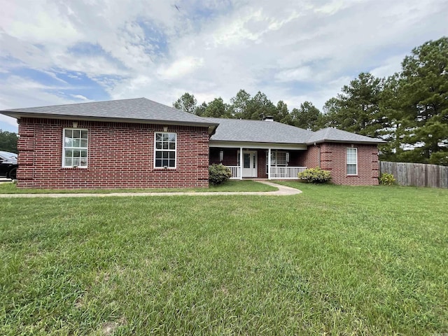 ranch-style house featuring covered porch, brick siding, fence, and a front lawn