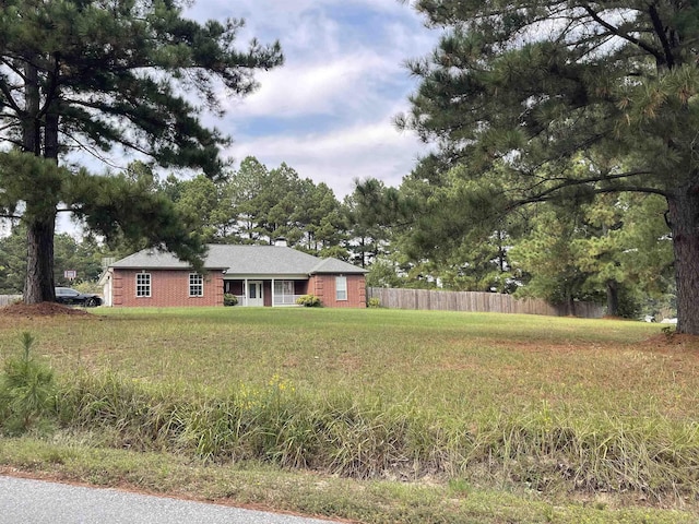 view of front facade featuring a chimney, fence, a front lawn, and brick siding