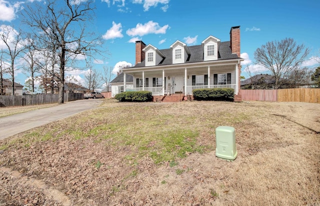 cape cod home with covered porch, a front lawn, a chimney, and fence