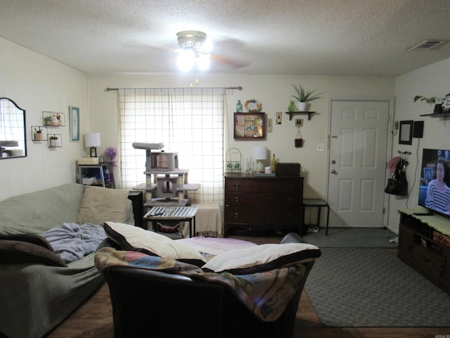 living area with visible vents, a textured ceiling, wood finished floors, and a ceiling fan