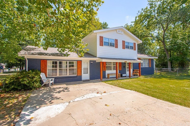 view of front of house featuring brick siding, fence, a porch, and a front yard