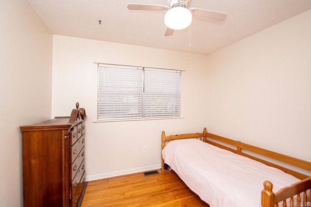 bedroom featuring visible vents, light wood-style floors, ceiling fan, a textured ceiling, and baseboards