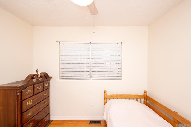 bedroom featuring light wood-style flooring, visible vents, ceiling fan, and baseboards