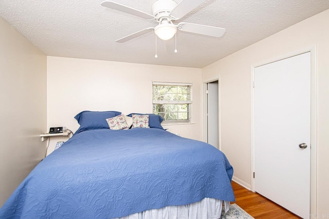 bedroom featuring a textured ceiling, a ceiling fan, and wood finished floors