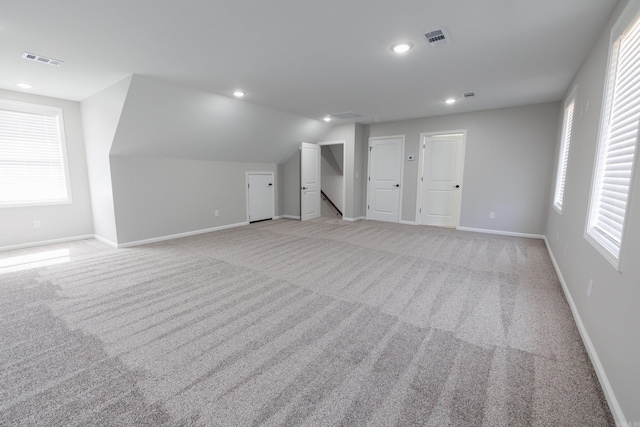 additional living space with baseboards, recessed lighting, visible vents, and light colored carpet