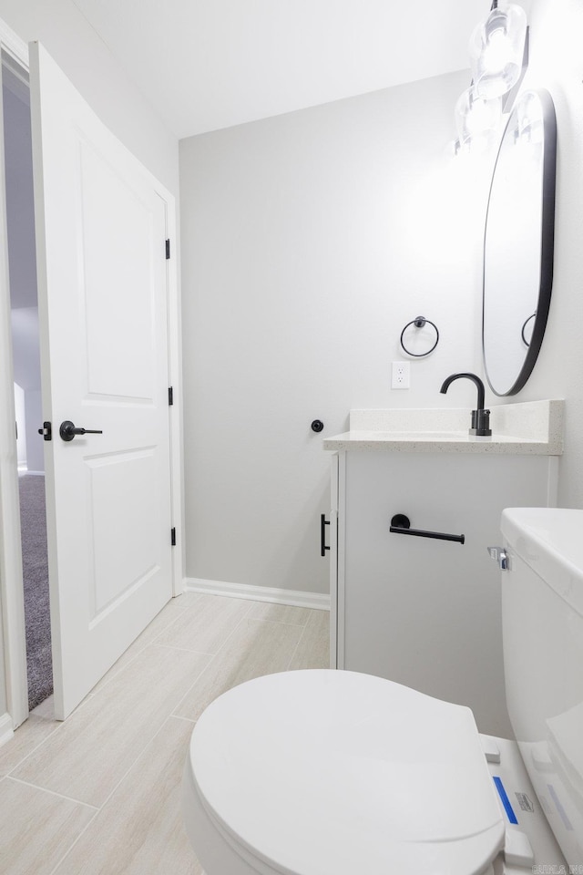 bathroom featuring vanity, toilet, and baseboards