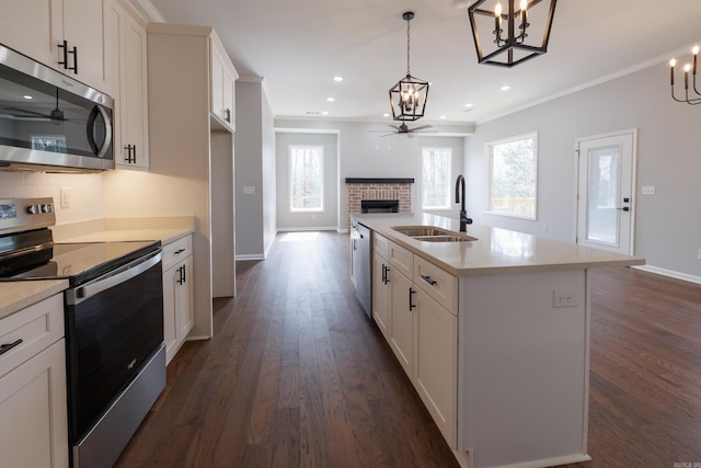 kitchen featuring a ceiling fan, appliances with stainless steel finishes, open floor plan, a brick fireplace, and a sink