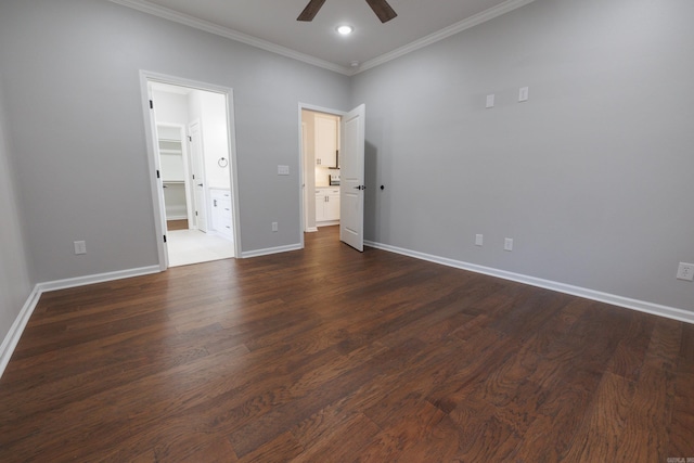 unfurnished bedroom with dark wood-type flooring, a ceiling fan, baseboards, a spacious closet, and ornamental molding