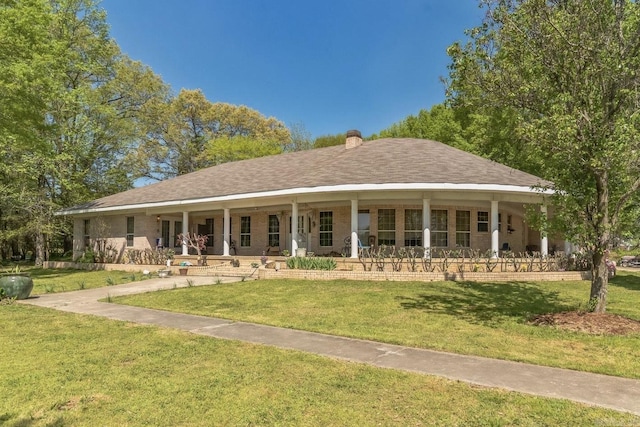 view of front of home featuring covered porch, a chimney, brick siding, and a front yard