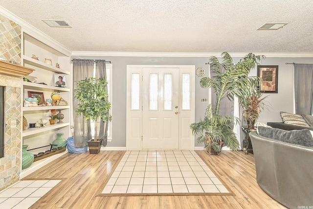 foyer entrance featuring a textured ceiling, visible vents, and light wood-style floors