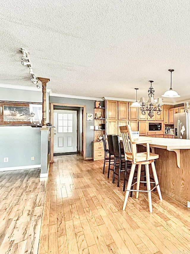 kitchen featuring a breakfast bar area, light countertops, open shelves, stainless steel fridge, and crown molding