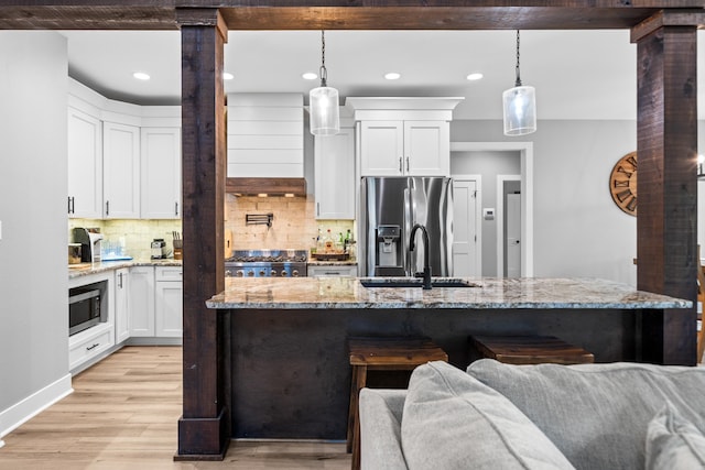 kitchen featuring light wood finished floors, white cabinetry, stainless steel appliances, and a sink