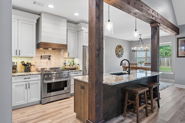 kitchen with a sink, appliances with stainless steel finishes, custom exhaust hood, tasteful backsplash, and decorative columns