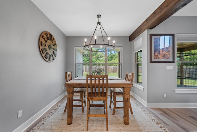 dining room with a chandelier, beamed ceiling, baseboards, and wood finished floors