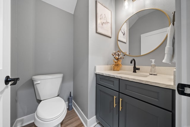 bathroom with baseboards, vanity, toilet, and wood finished floors