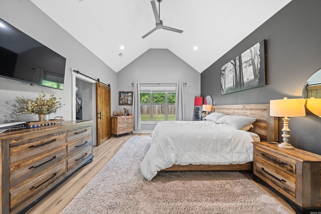 bedroom featuring ceiling fan, high vaulted ceiling, a barn door, light wood-style flooring, and access to outside