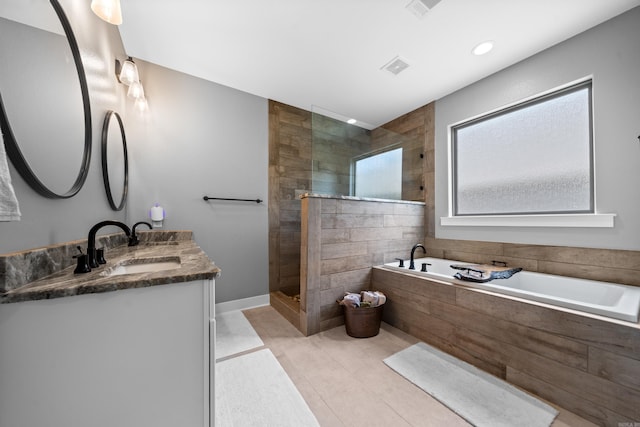 full bath with double vanity, visible vents, a garden tub, a walk in shower, and a sink