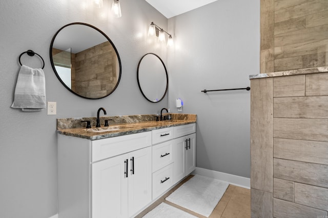 full bathroom featuring double vanity, baseboards, and a sink