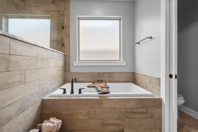 bathroom with toilet and a garden tub