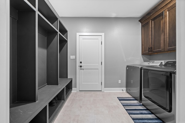 clothes washing area with washer and dryer, cabinet space, and baseboards