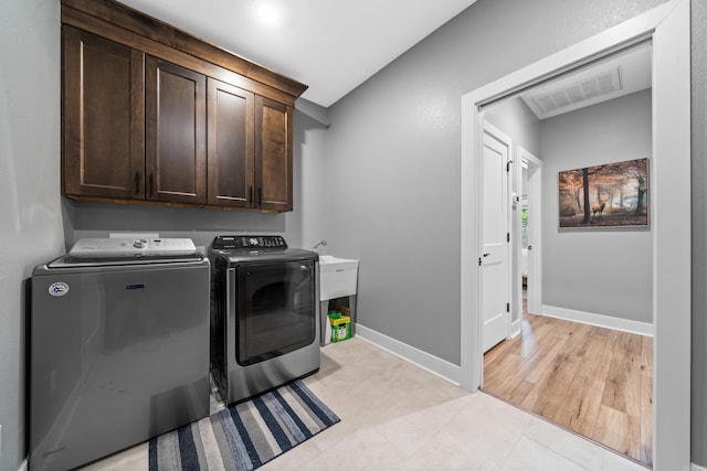 laundry room featuring light tile patterned floors, visible vents, cabinet space, washer and dryer, and baseboards