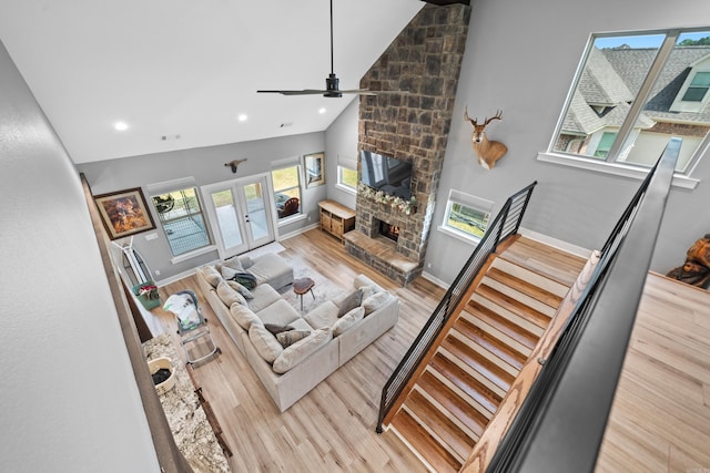 living area featuring high vaulted ceiling, french doors, wood finished floors, and a stone fireplace