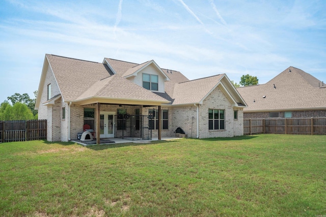 rear view of house with a lawn, a fenced backyard, french doors, a patio area, and brick siding