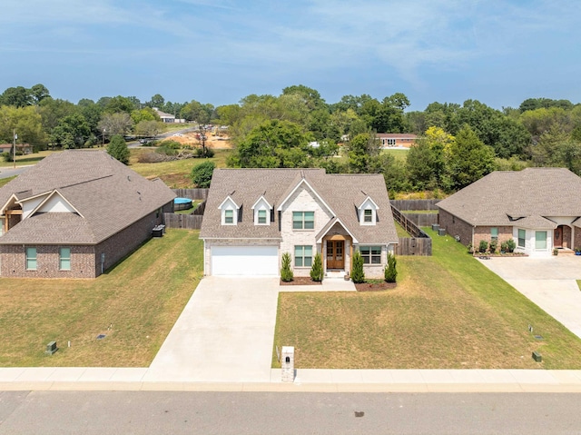 view of front of house featuring an attached garage, fence, concrete driveway, roof with shingles, and a front lawn