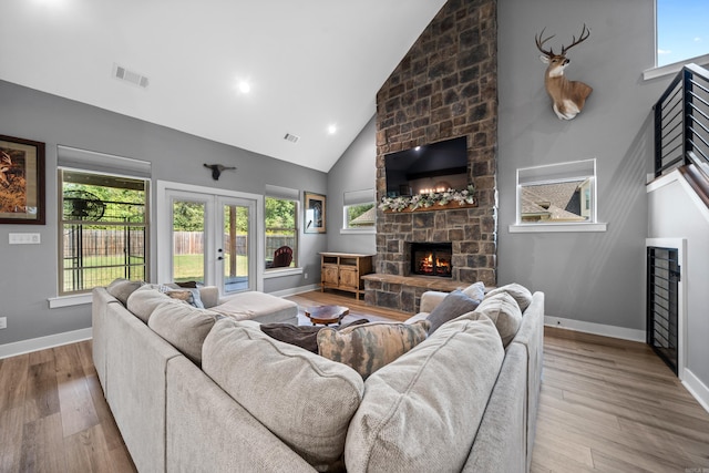 living area with french doors, a fireplace, wood finished floors, high vaulted ceiling, and baseboards