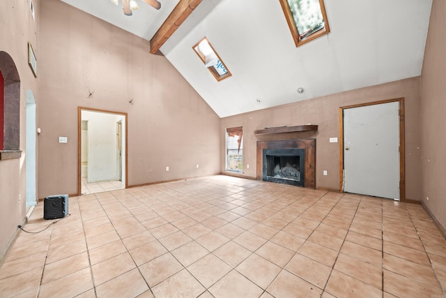 unfurnished living room featuring light tile patterned floors, high vaulted ceiling, a skylight, a fireplace, and beamed ceiling