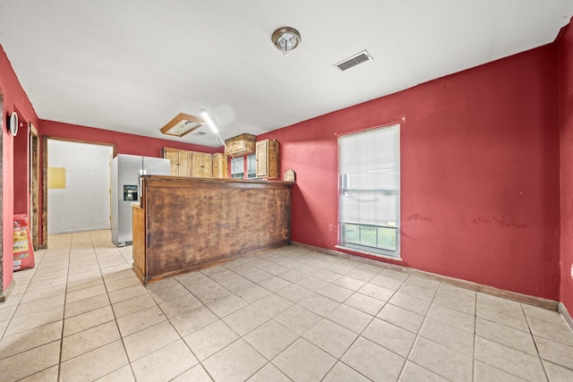 kitchen with light tile patterned flooring, visible vents, and stainless steel fridge with ice dispenser