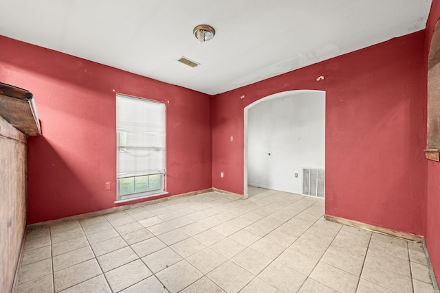 tiled empty room with visible vents and arched walkways