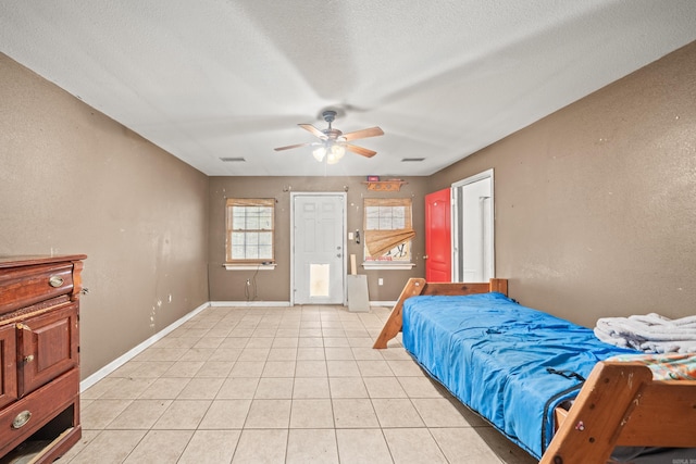 bedroom featuring light tile patterned floors, a ceiling fan, baseboards, and a textured ceiling