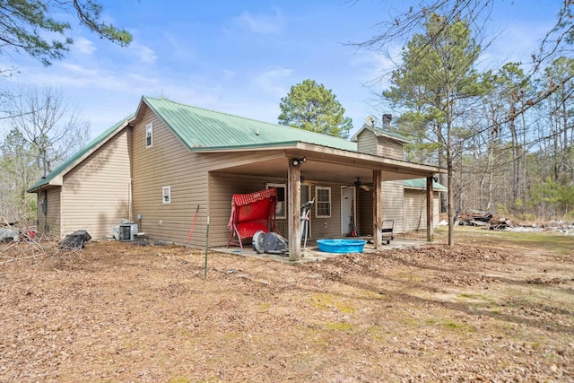 view of home's exterior with a patio, a chimney, a ceiling fan, metal roof, and cooling unit