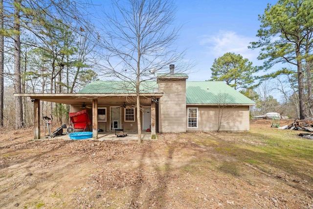 rear view of house featuring a patio area, a chimney, metal roof, and a ceiling fan